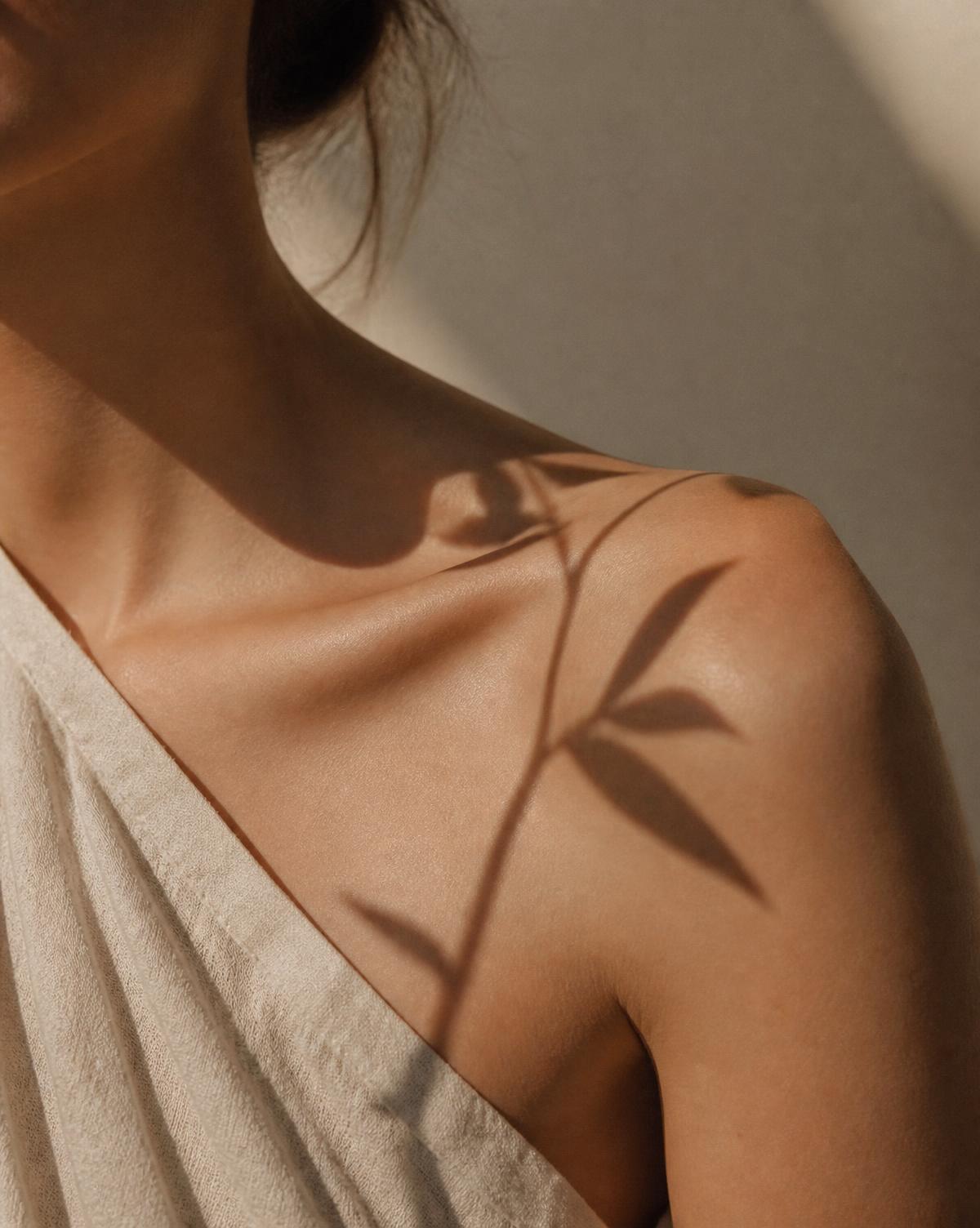 Daylight and a leaf shadow falling across a woman's shoulder